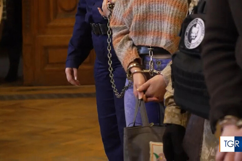 Nella foto, Ilaria Salis in manette mentre viene accompagnata nell'aula di tribunale con due agenti.
Fonte Foto TGR